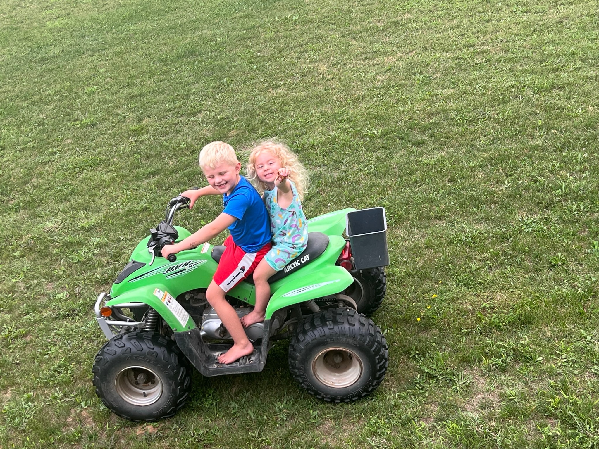 Two kids riding ATV outdoors